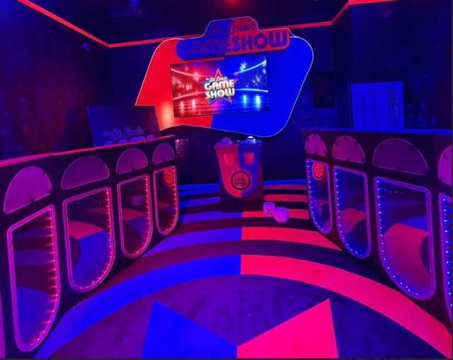 Complete game show set with curved lit podiums, host desk and branded screen